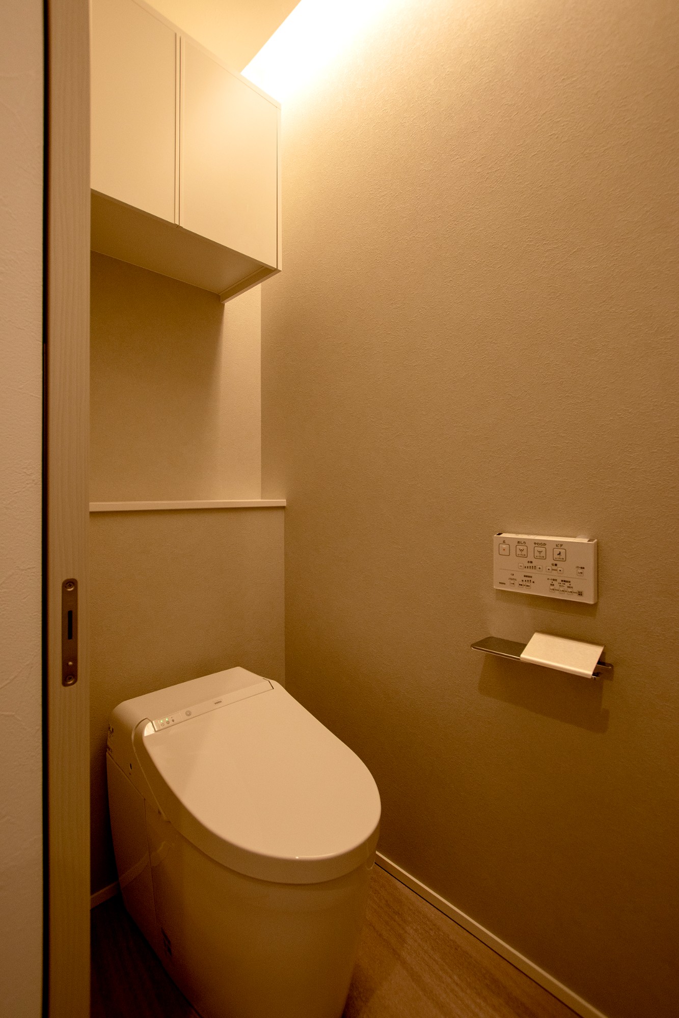 グレーホワイトのガルバと塗り壁で彩る「コの字型テラスと吹抜け」のある住まいのトイレ写真