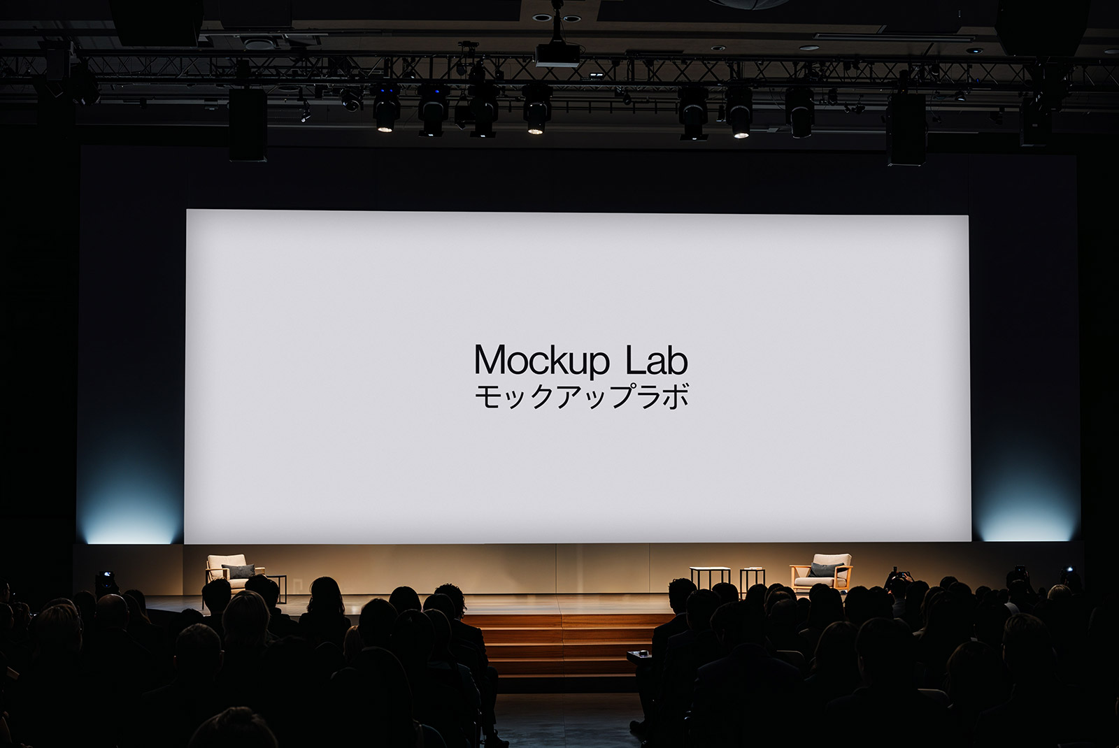 Front view of a modern conference stage with large central screen and side banners.