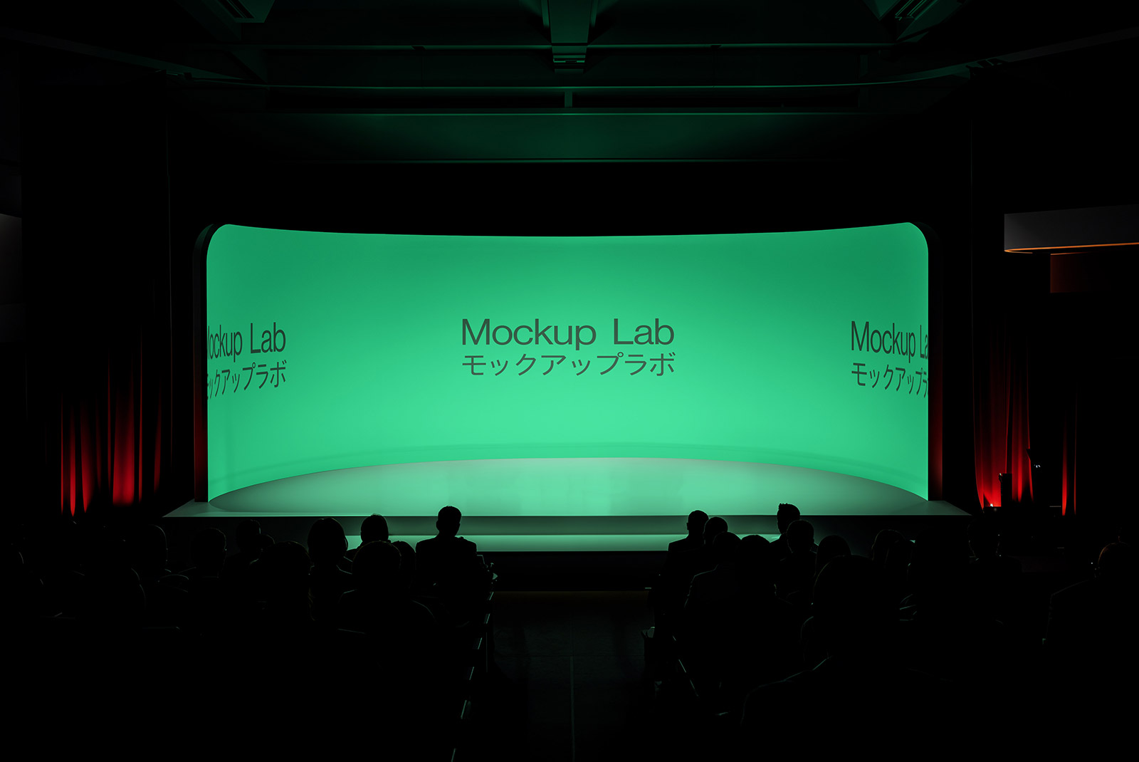 Front view of a large conference stage with a prominent central screen and two side screens.
