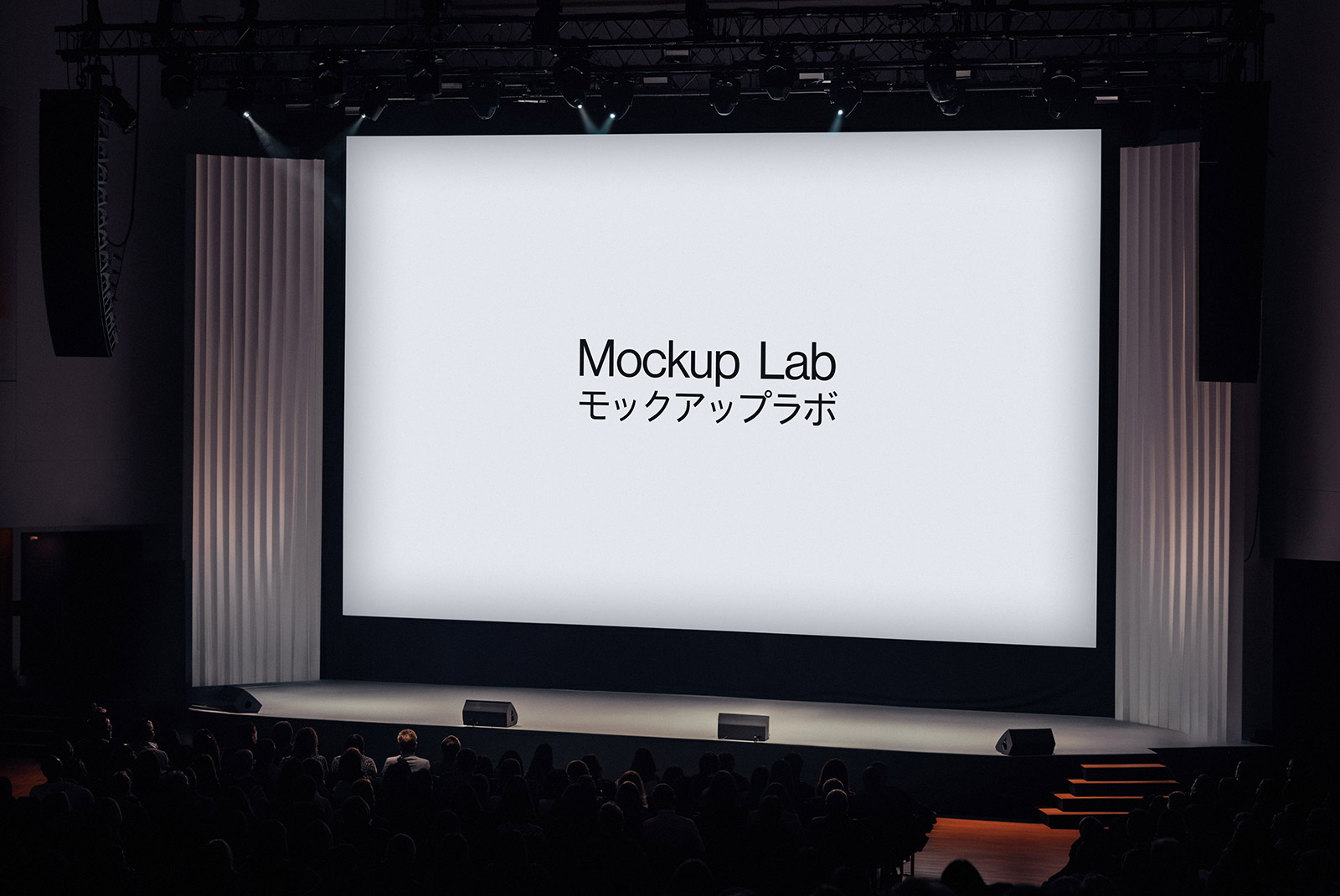Front view of a large conference stage with a prominent central screen and two side screens.