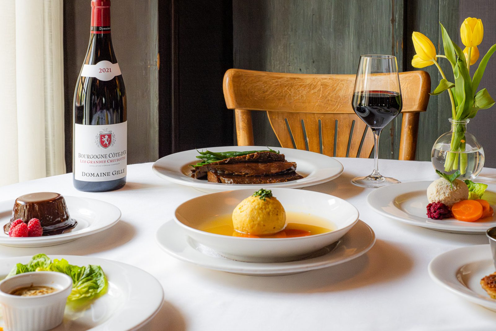 Spread of Rosh Hashanah dishes including Matzo Ball Soup, brisket, flourless chocolate cake, and a bottle of wine.