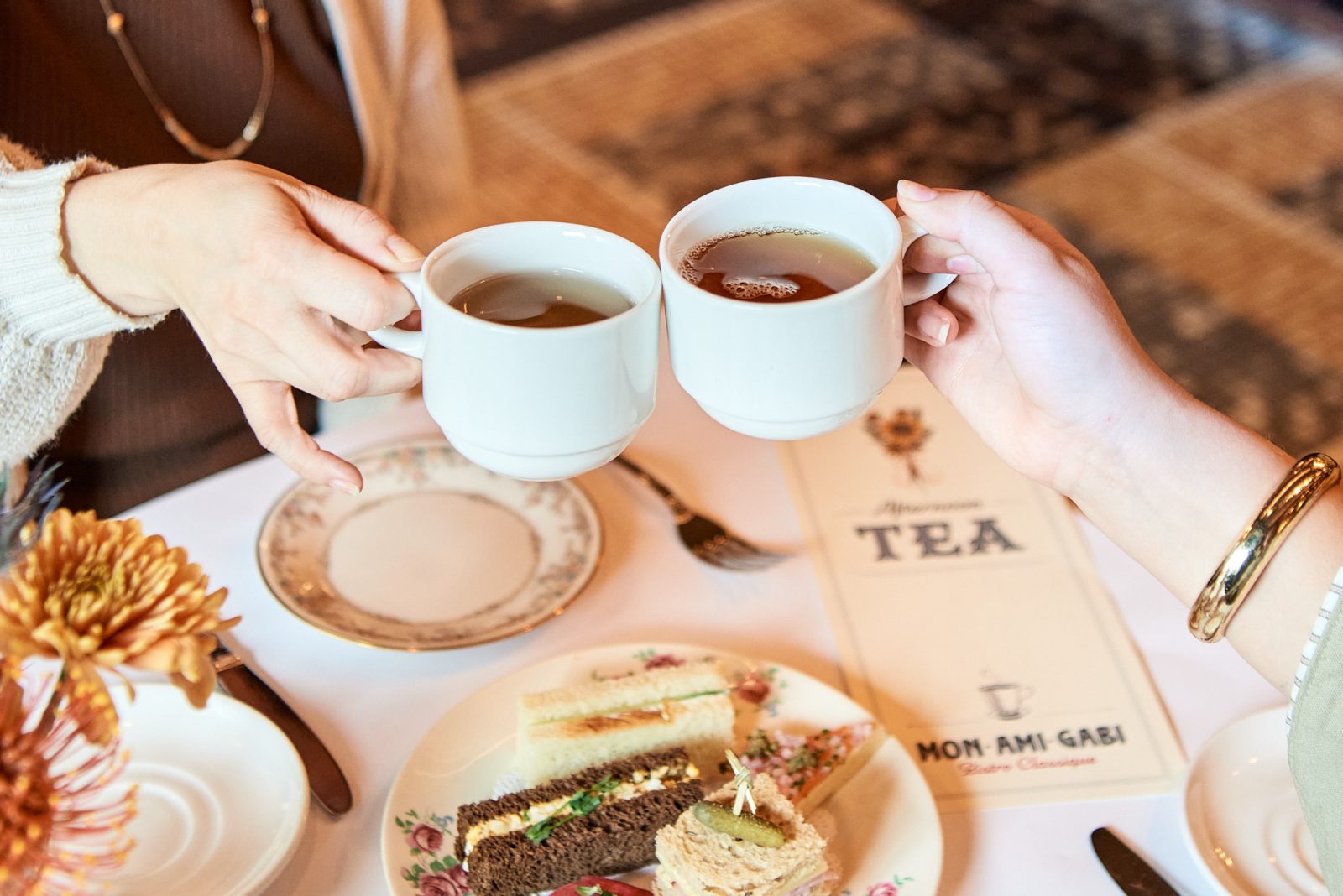 Two people cheersing their cups of tea at the Autumn Afternoon Tea.