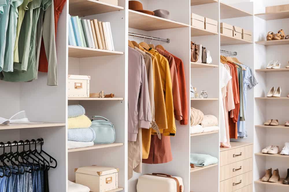 A large walk in closet with colorful clothing and stylish organization