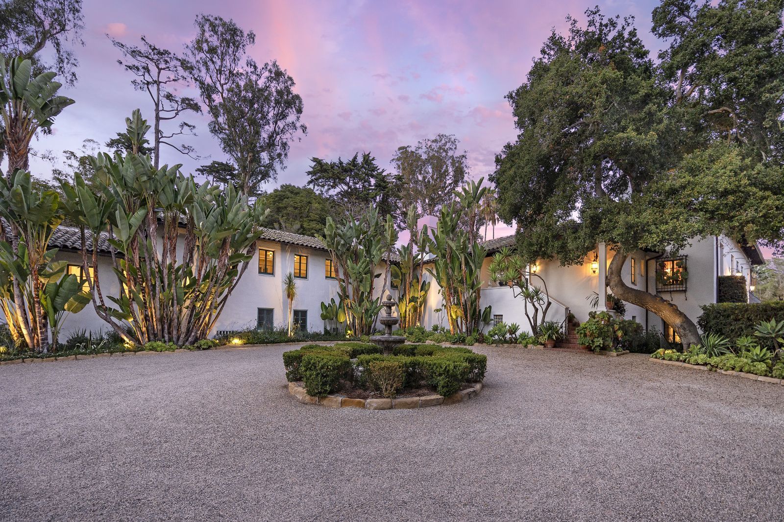 The motor court and main residence of a world class Montecito estate designed by architect George Washington Smith, at sunset with a beautiful pink and purple sky