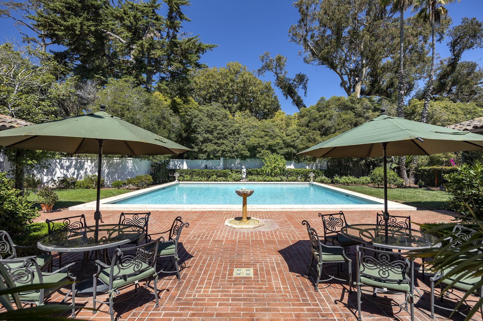 A sparkling pool and brick surround amidst lush, manicured greenery and large trees