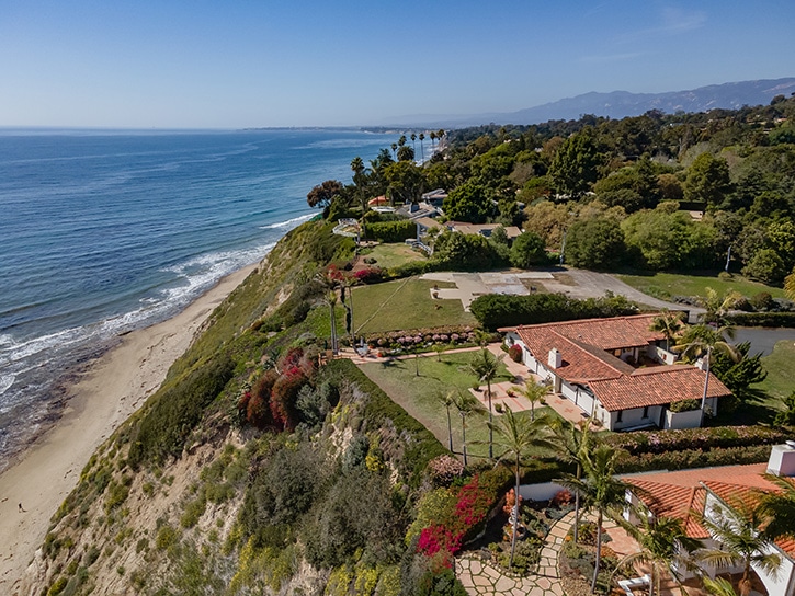 An estate sitting on a bluff overlooking the beach in an aerial view
