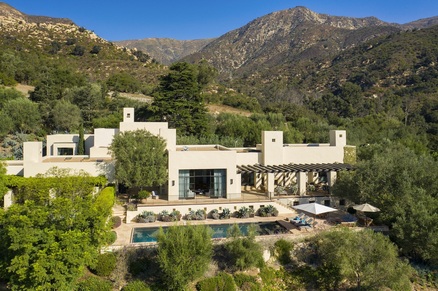 Birds Eye View of a luxury home for sale in Santa Barbara framed by mountains and blue sky