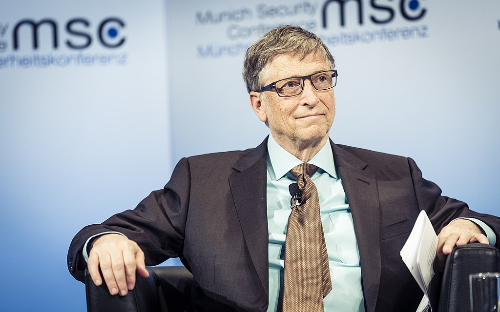 Bill Gates sitting in a chair on a stage.