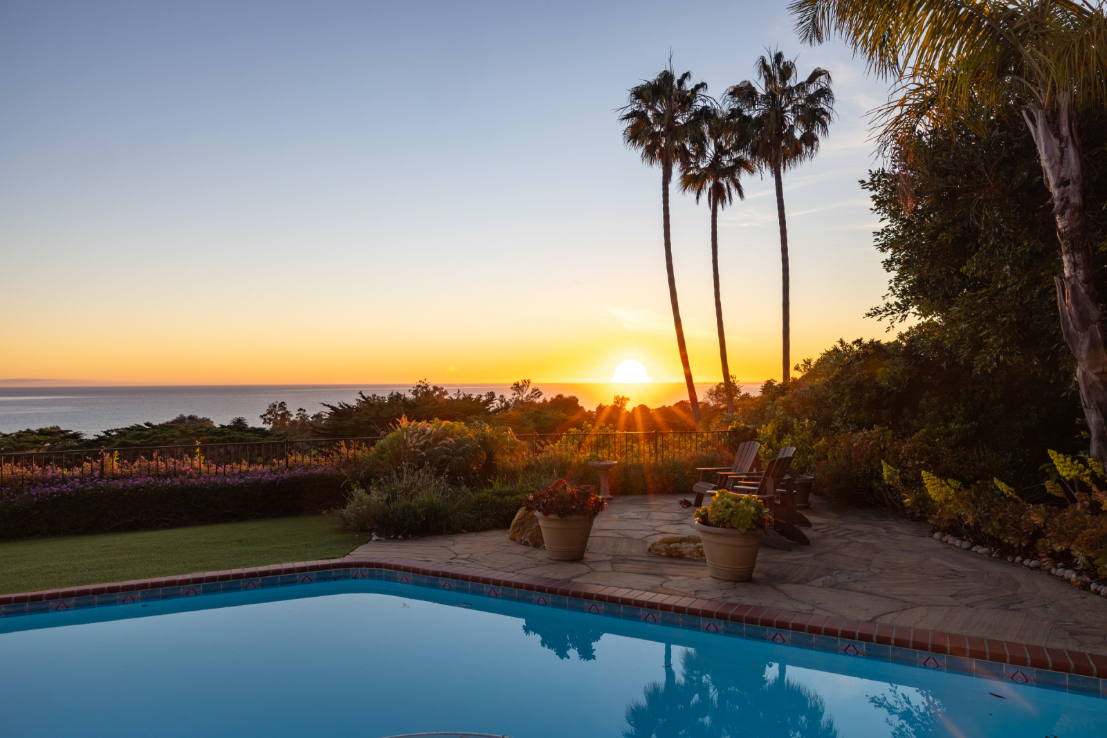 Montecito backyard with pool, ocean views, palm trees, and sunset patio seating overlooking the Pacific Ocean.