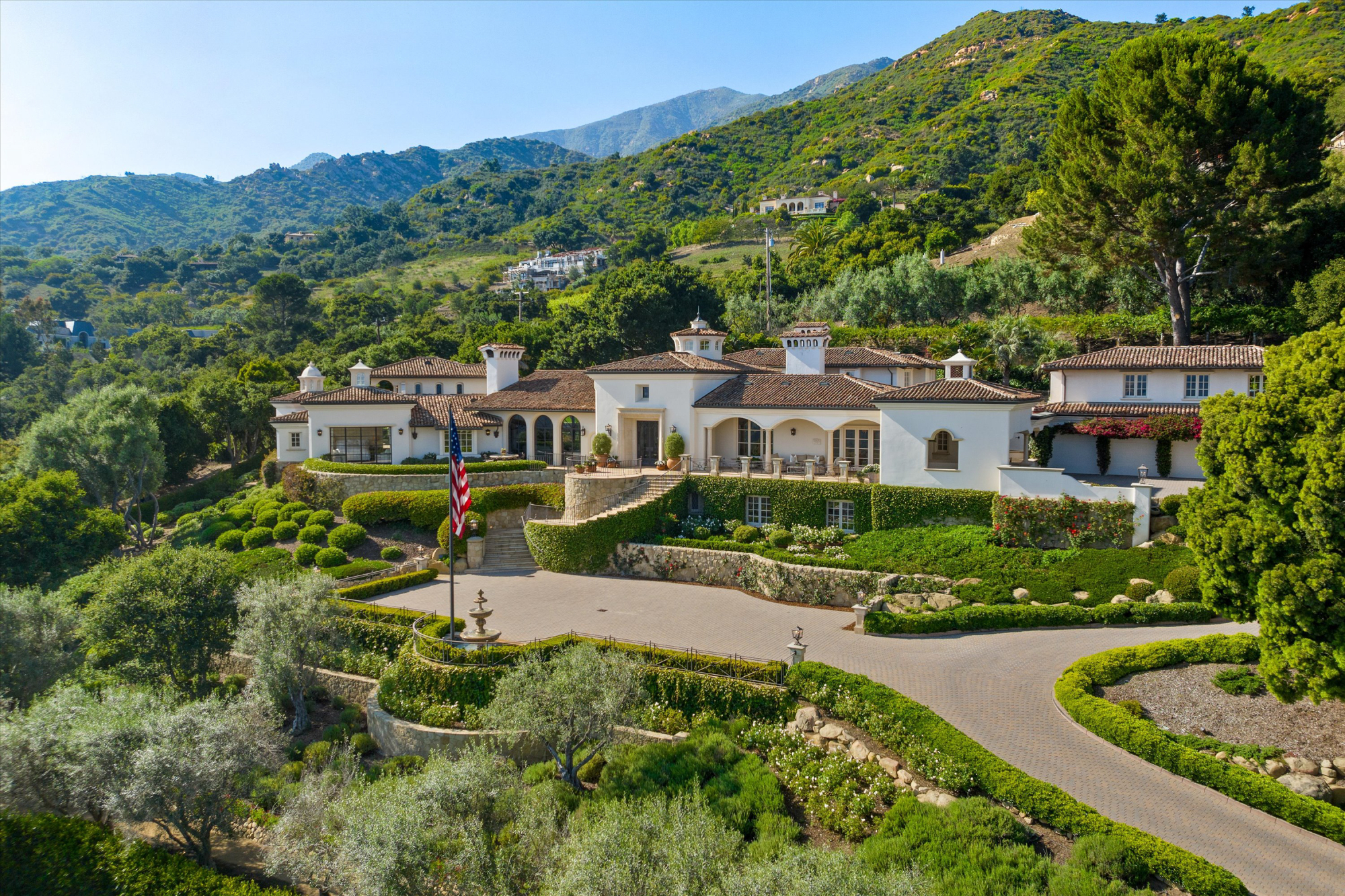 Grand Santa Barbara estate with Mediterranean architecture, manicured gardens, a circular driveway, and mountain views.