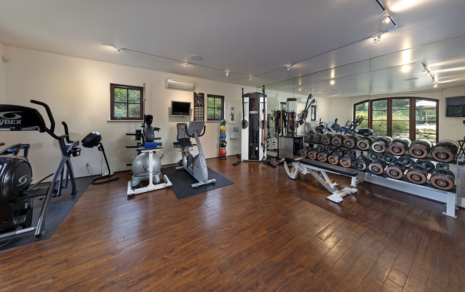 A large private at-home gym with a wood floor and state of the art equipment.