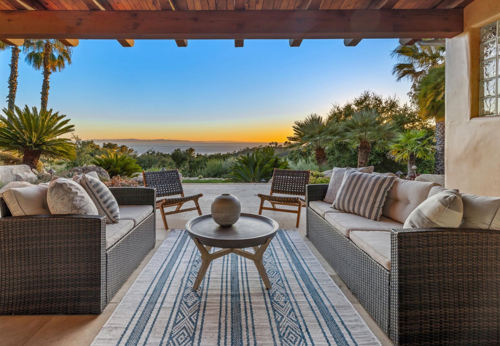 A beautiful veranda with stylish outdoor furnishings, looking out to the ocean at sunset at a luxury Santa Barbara home.