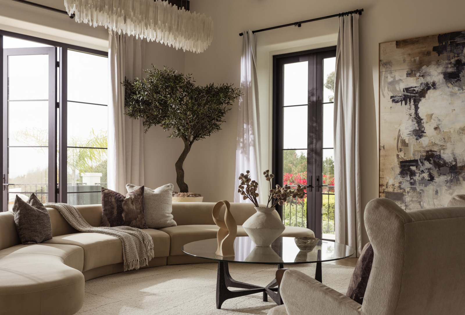 Sophisticated Montecito living room featuring curved seating, floor-to-ceiling windows, designer furnishings, and abundant natural light.