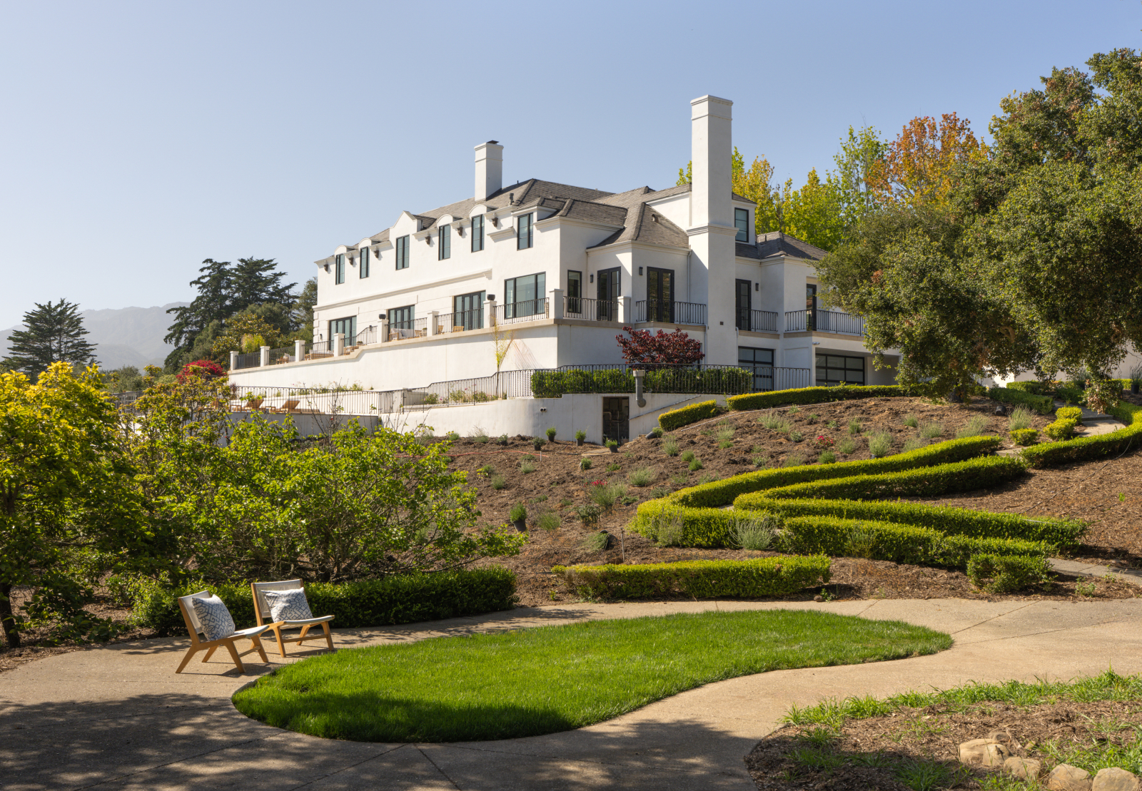 Elegant Montecito residence overlooking manicured gardens, walking paths, and mature landscaping with the Santa Ynez Mountains in the distance.