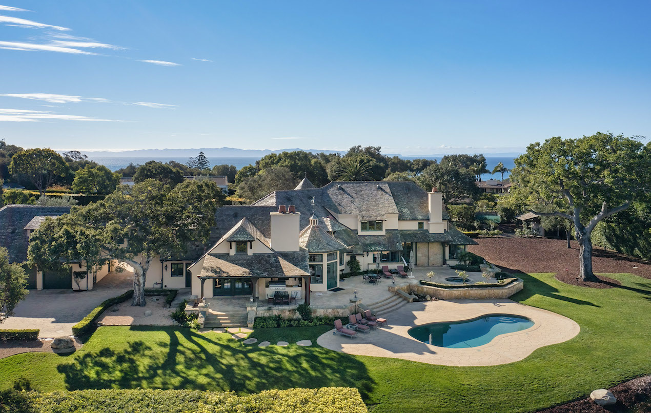 A bird's eye view of an estate in hope ranch with a sparking pool in the foreground and the Pacific Ocean in the background