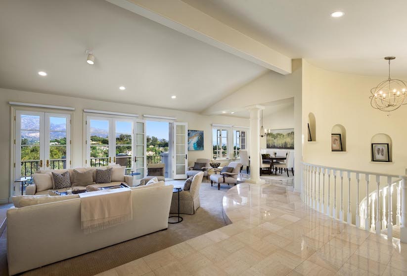 The living room of a luxury condo for sale with windows overlooking the ocean