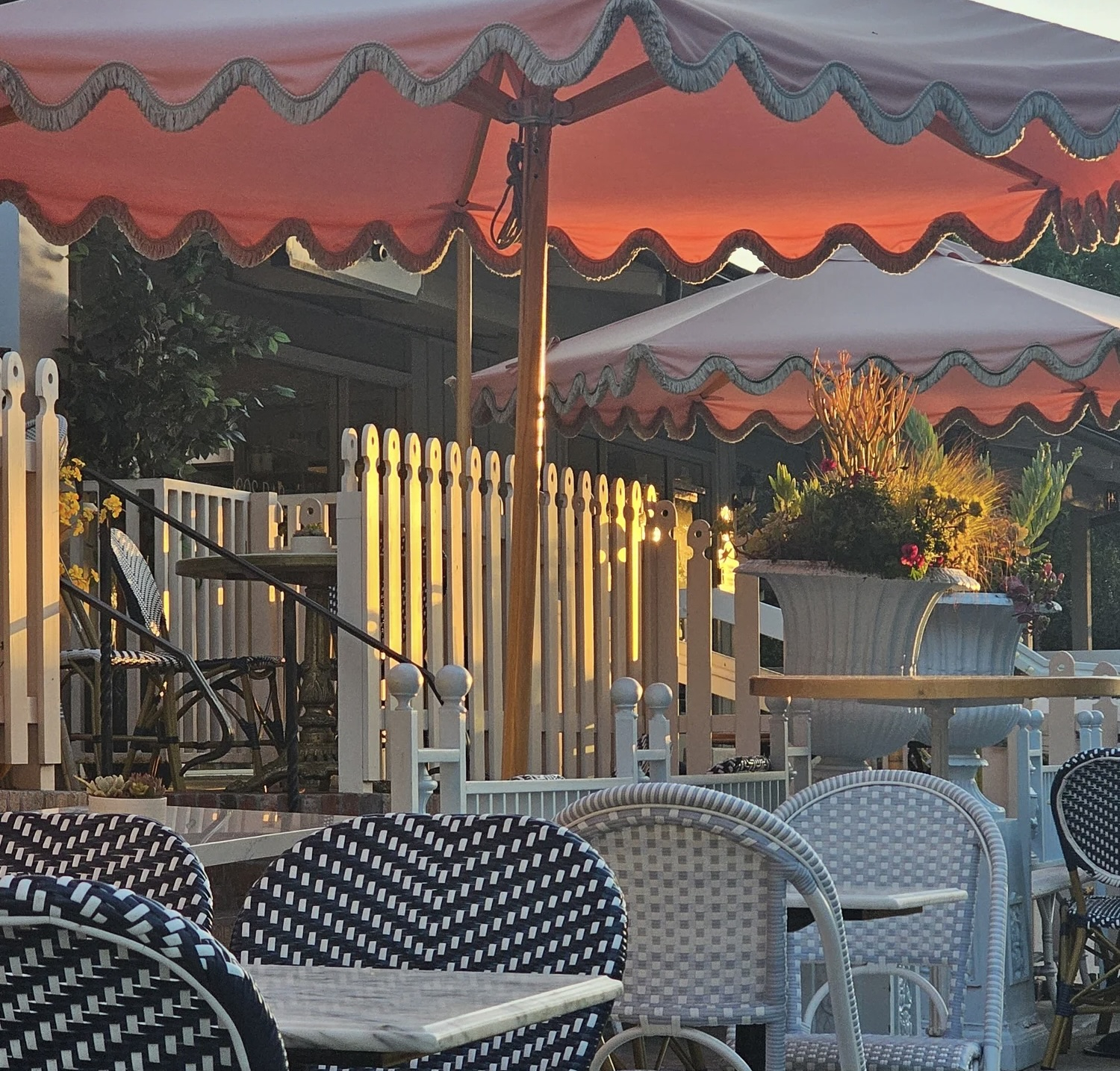 Casual outside dining tables and chairs with a colorful umbrella.