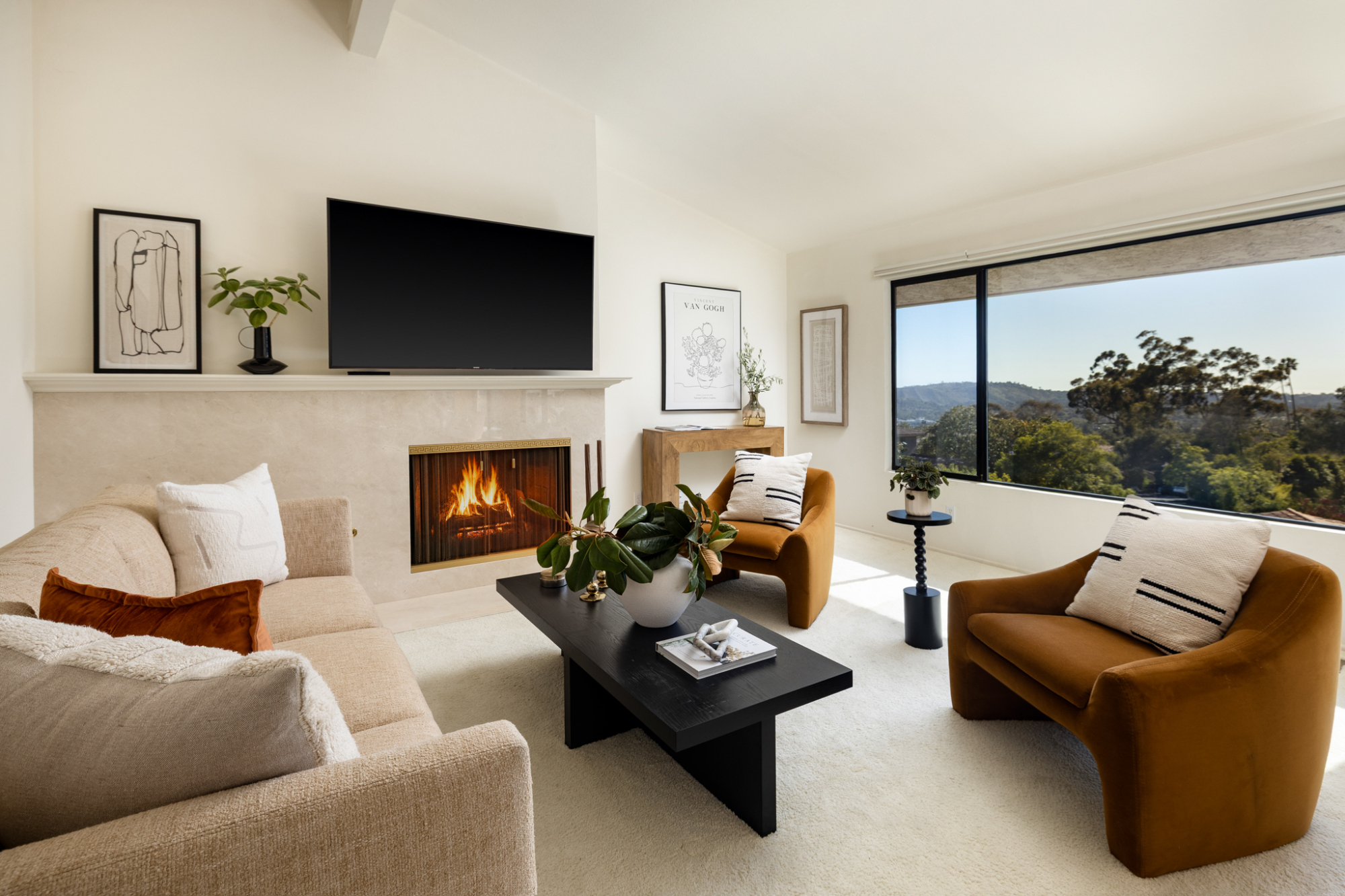 Bright Santa Barbara living room with fireplace, modern furnishings and large windows overlooking green hills.