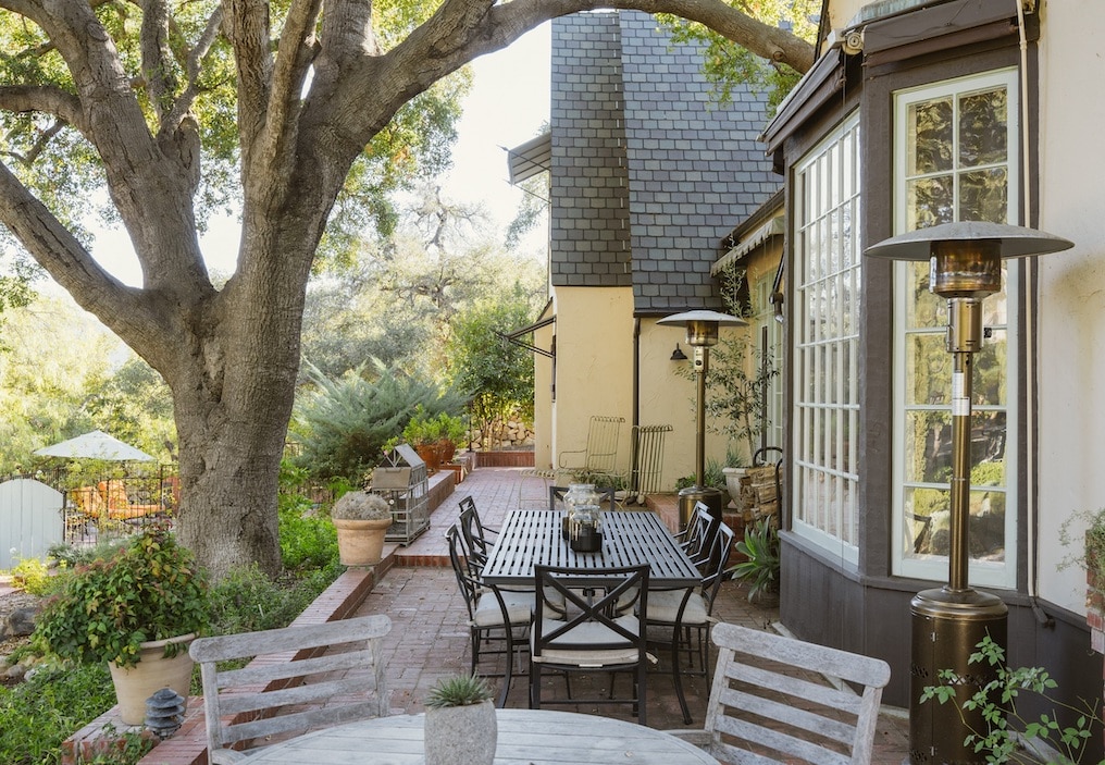 An outddor patio wiht a stately tree handgng over.