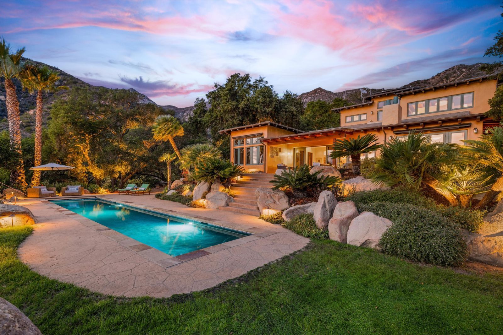 The backyard of a luxury home with a swimming pool and beautiful sunset.