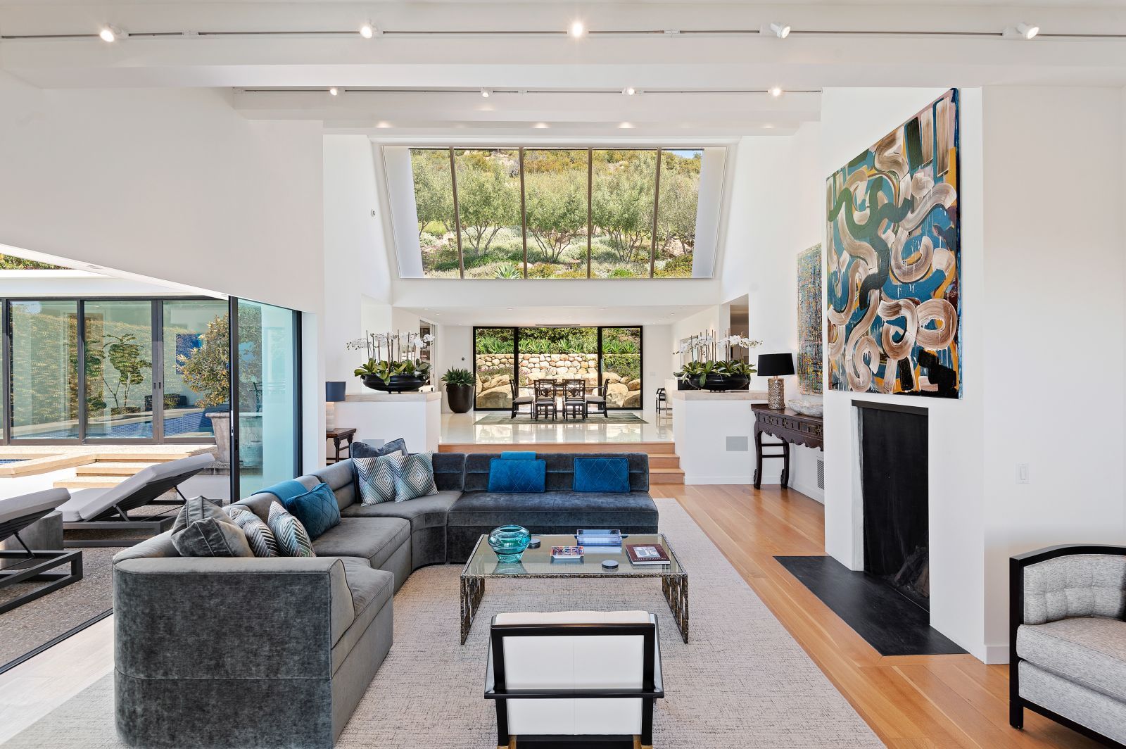 A luxury living room featuring a grouping of atelier windows along with high end furniture, high ceilings and a fireplace.