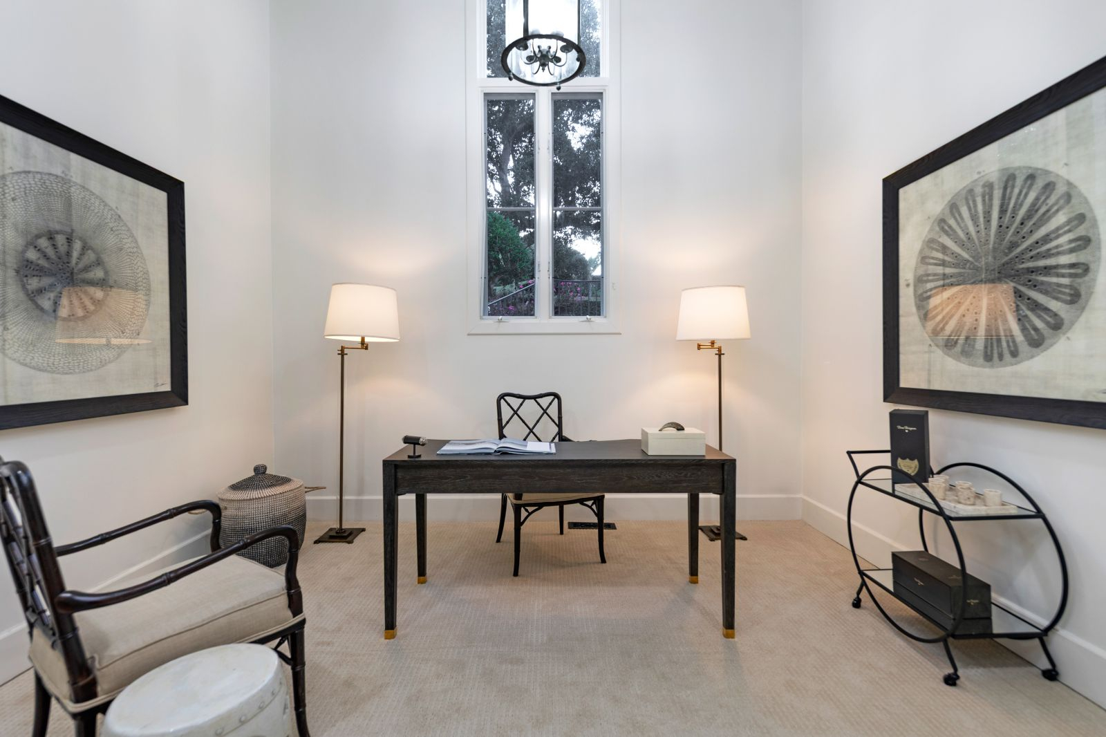 Two floor lamps and overhead lighting illuminate a black and while home office.