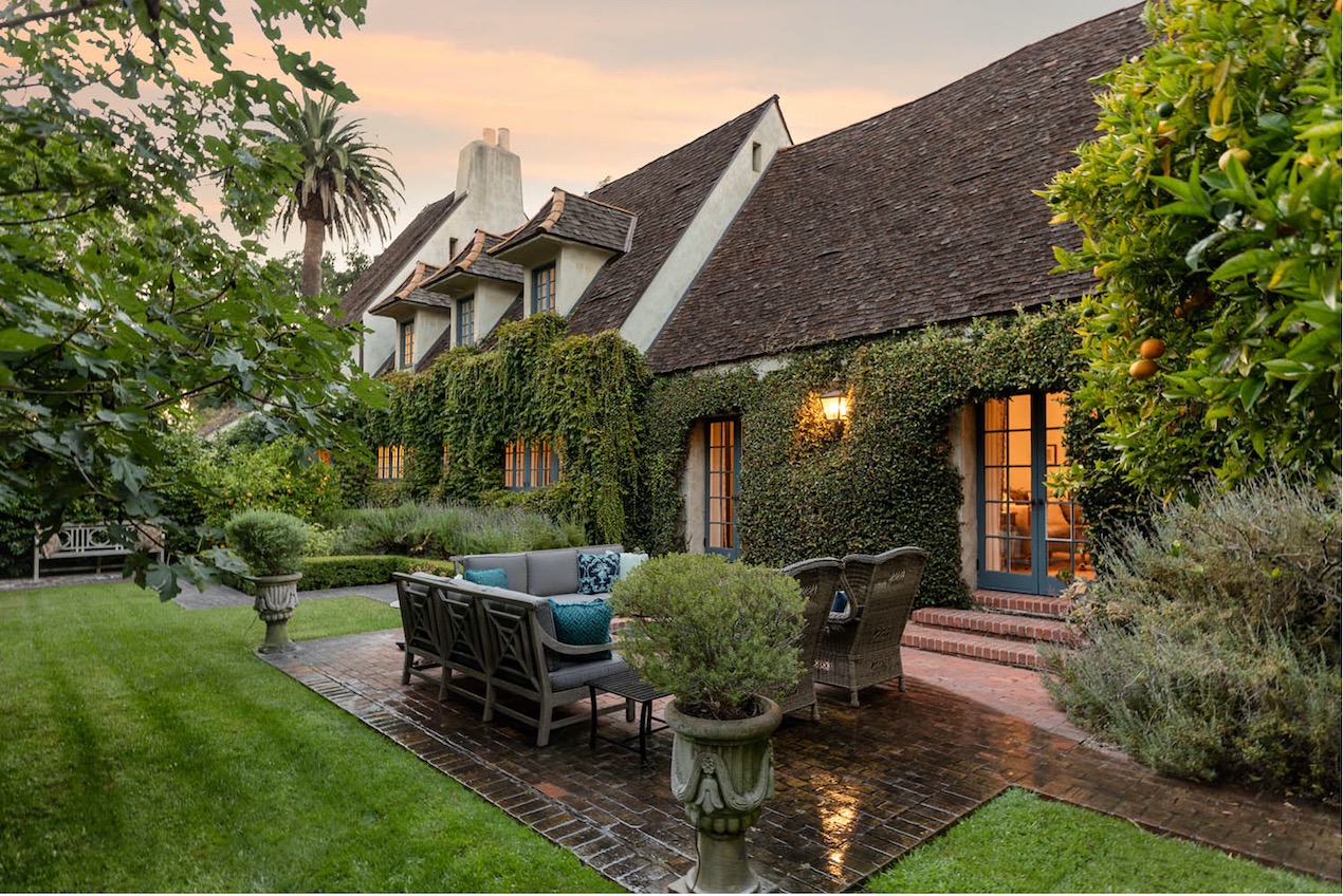 Side yard of a beautiful Montecito home with ivy growing on the wall and a cozy patio in the foreground.