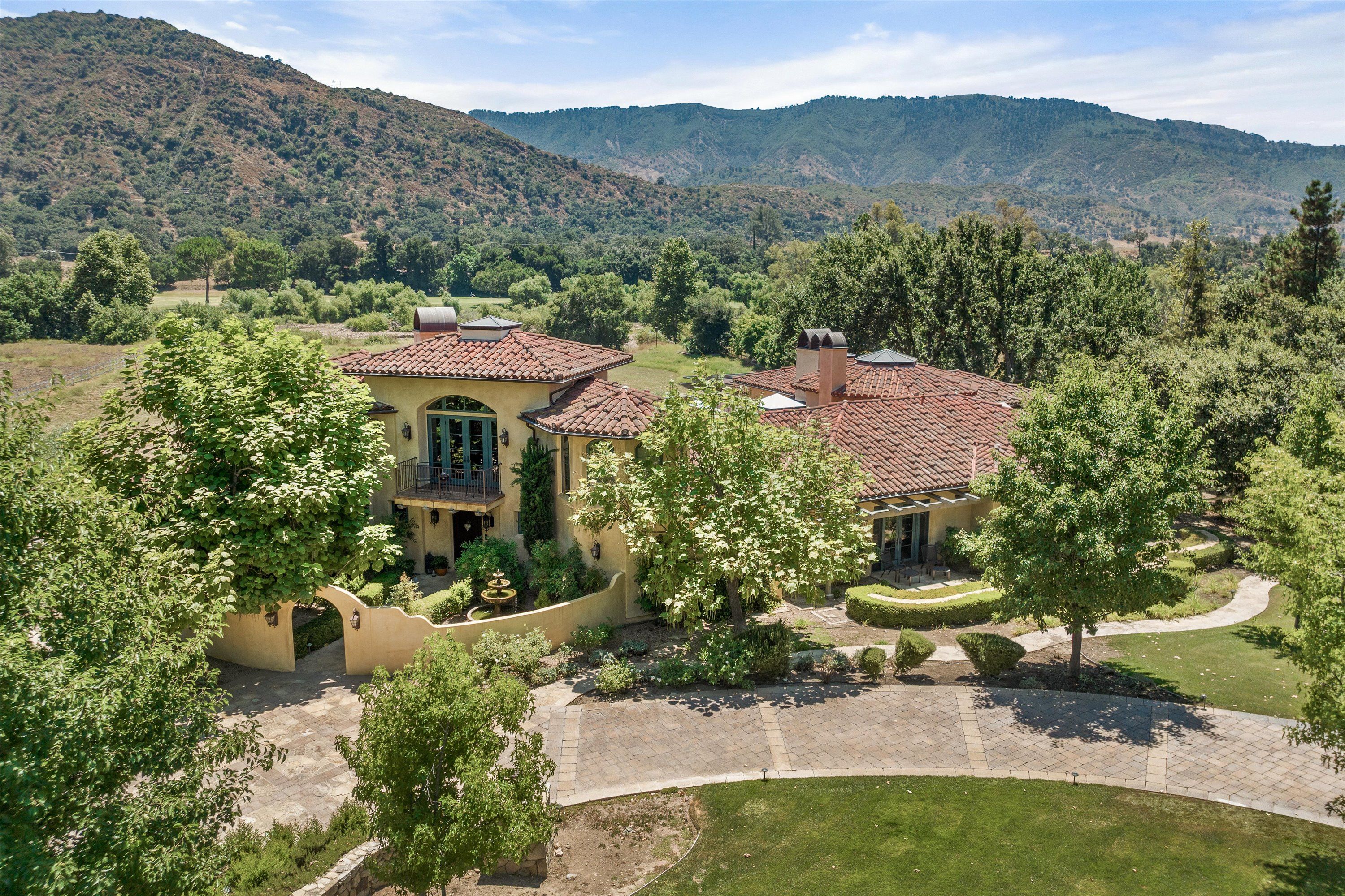 A luxury Ojai home with mountains in the background and a red tiled roof