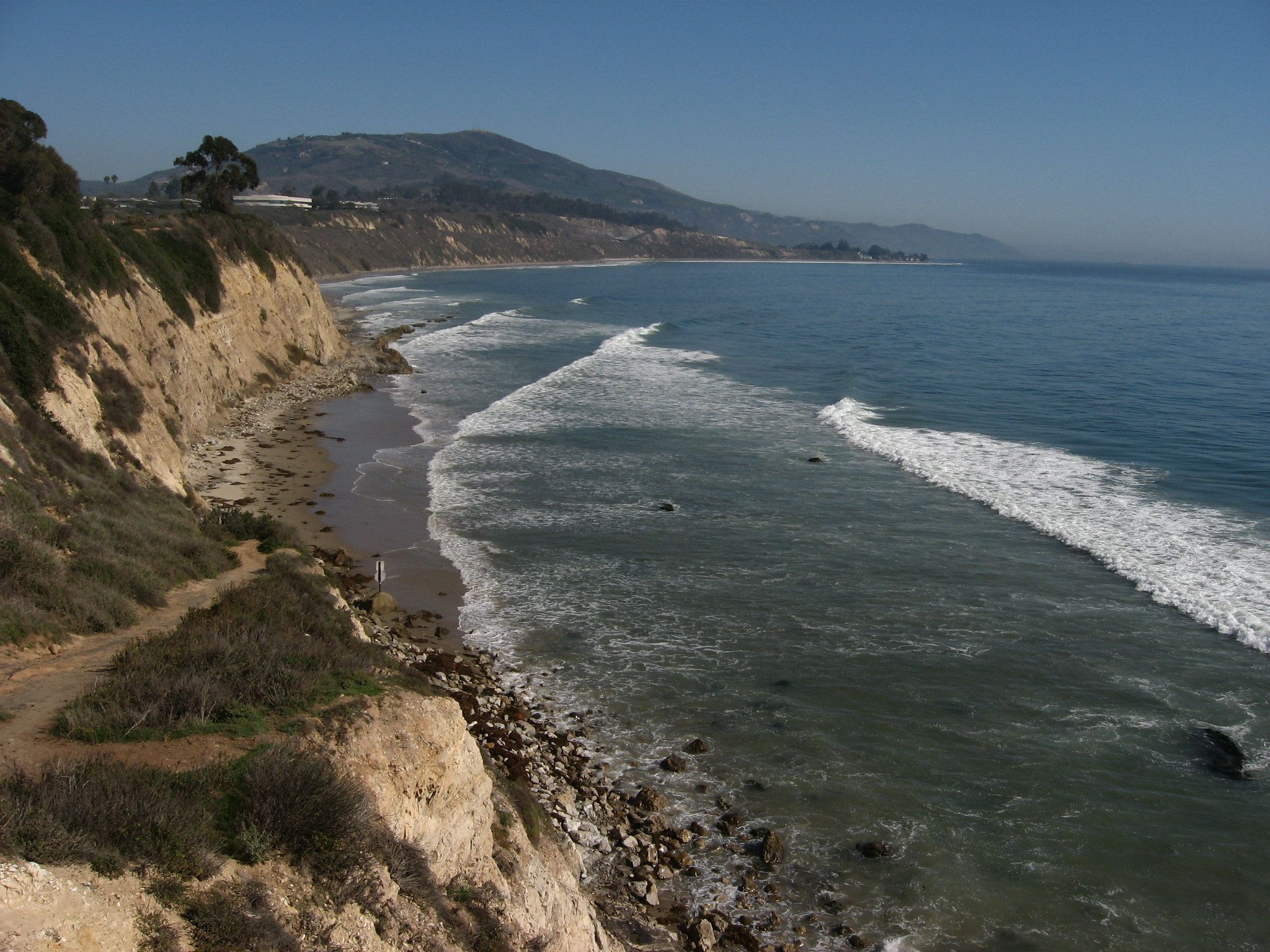 Sand bluffs above the beach and whitecapped ocean waves at Carpinteria Bluffs Nature Preserve in Santa Barbara.