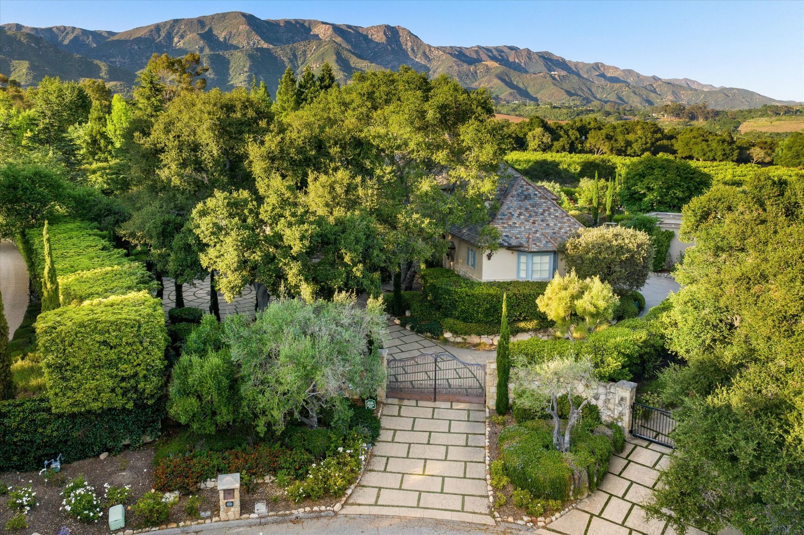 A luxury estate hidden behind lush trees and shrubs with the mountains in the background.