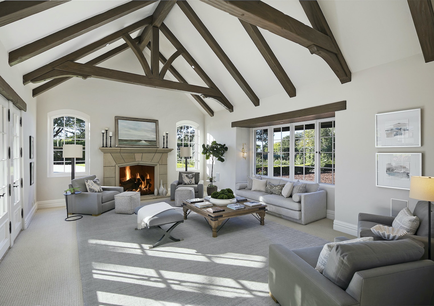 The living room of a well staged home with crisp white walls and just the right amount of furniture surrounding the glowing fireplace.