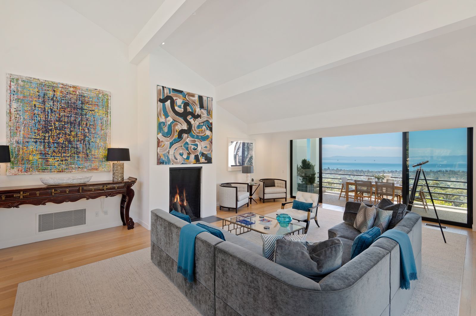 A luxury living room with floor to ceiling windows that look out to the Pacific Ocean, and with 2 large Abstract Impressionistic paintings on the walls.