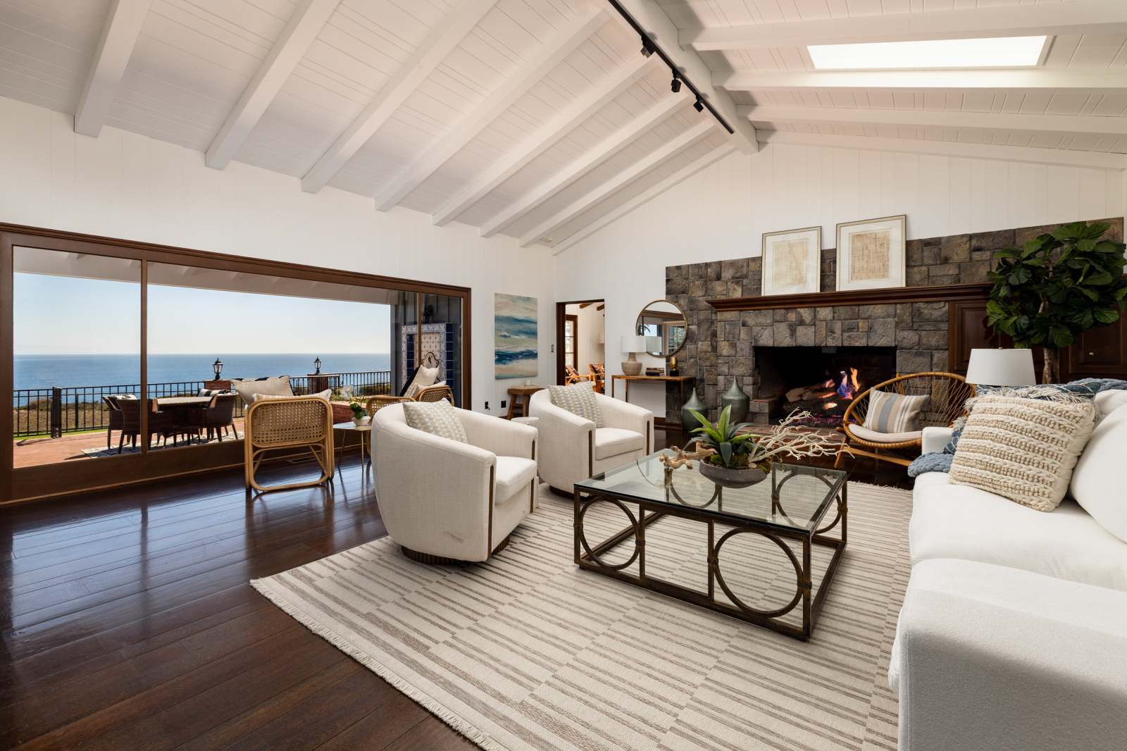A luxury living room with a view of the ocean through a wall of windows.