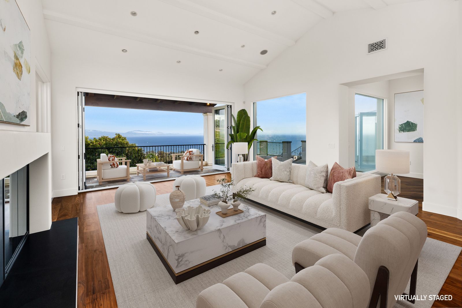 A luxury living room with a fireplace and open windows looking out to the ocean.