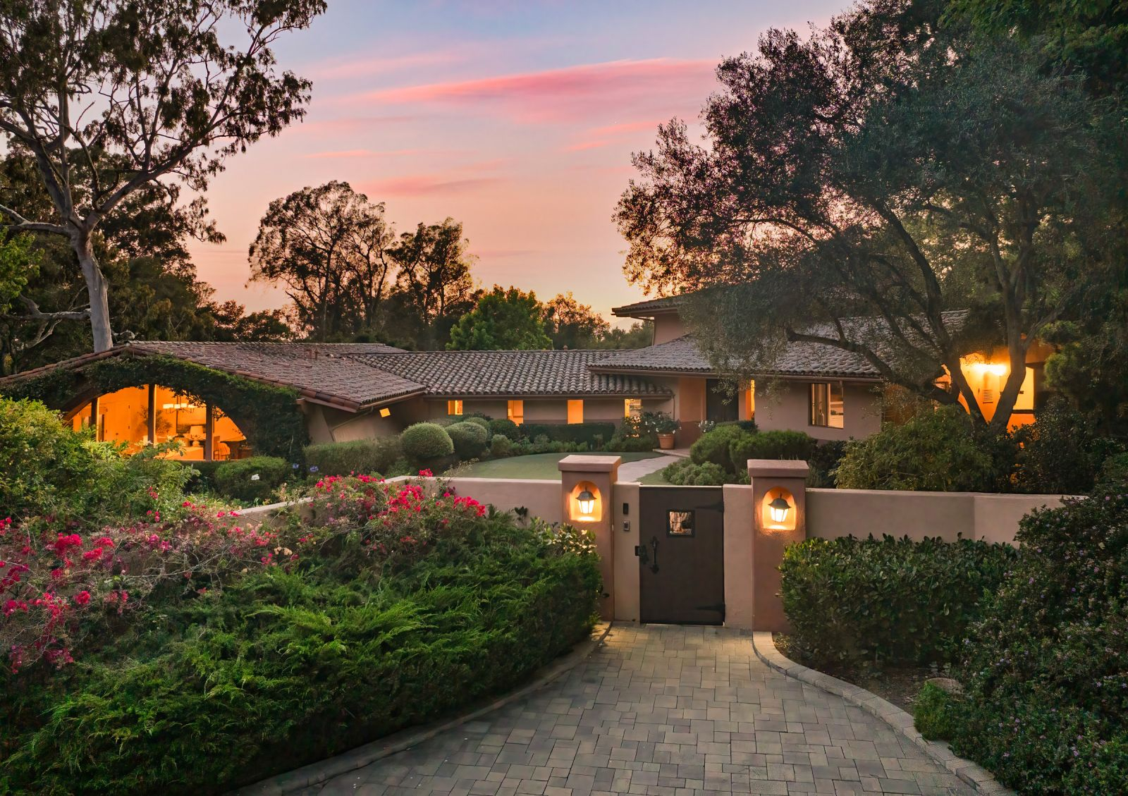 The outside of a luxury home with flowering hedges.