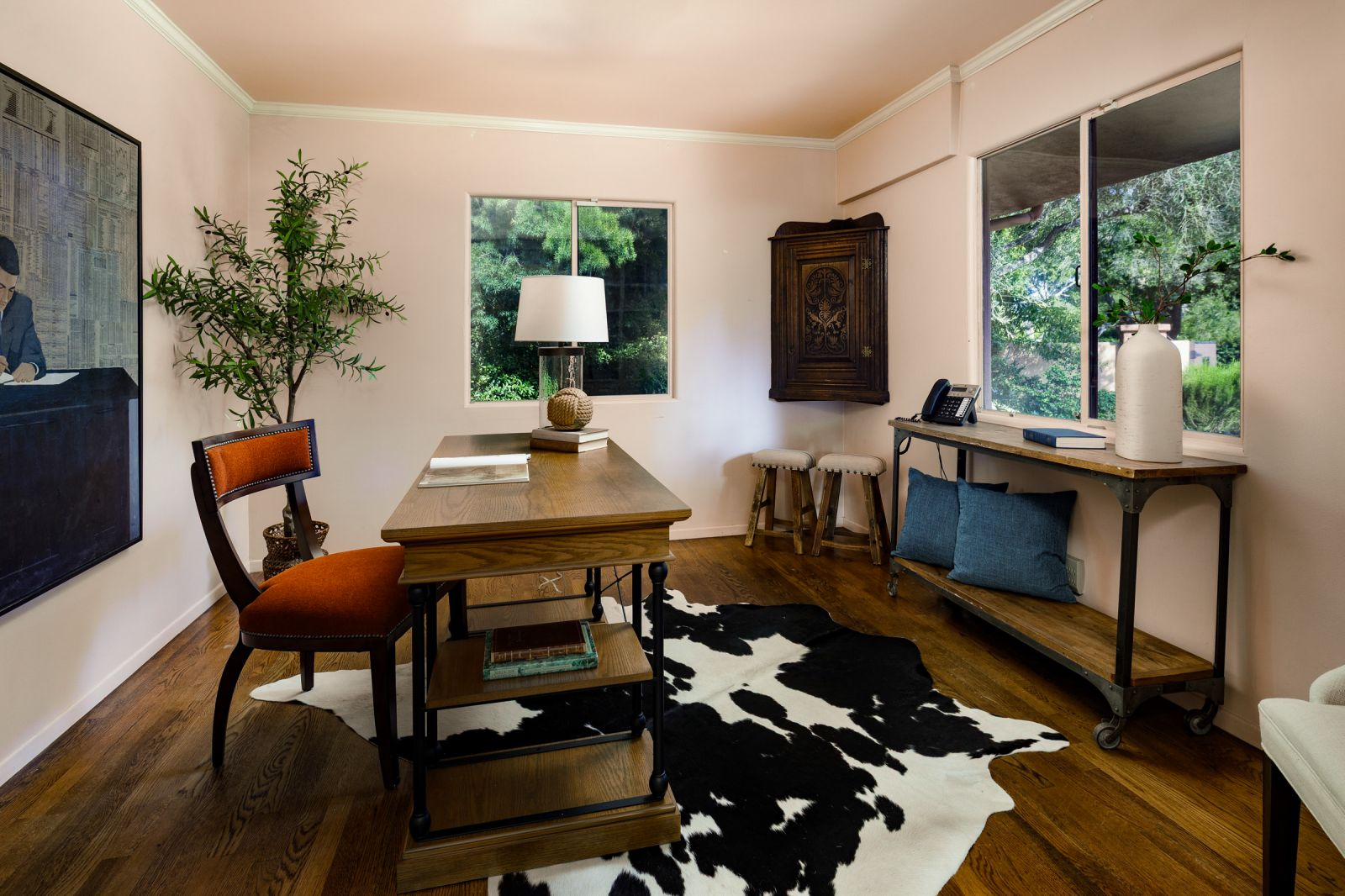 A luxury home office with a cow hide rug and a red desk chair.