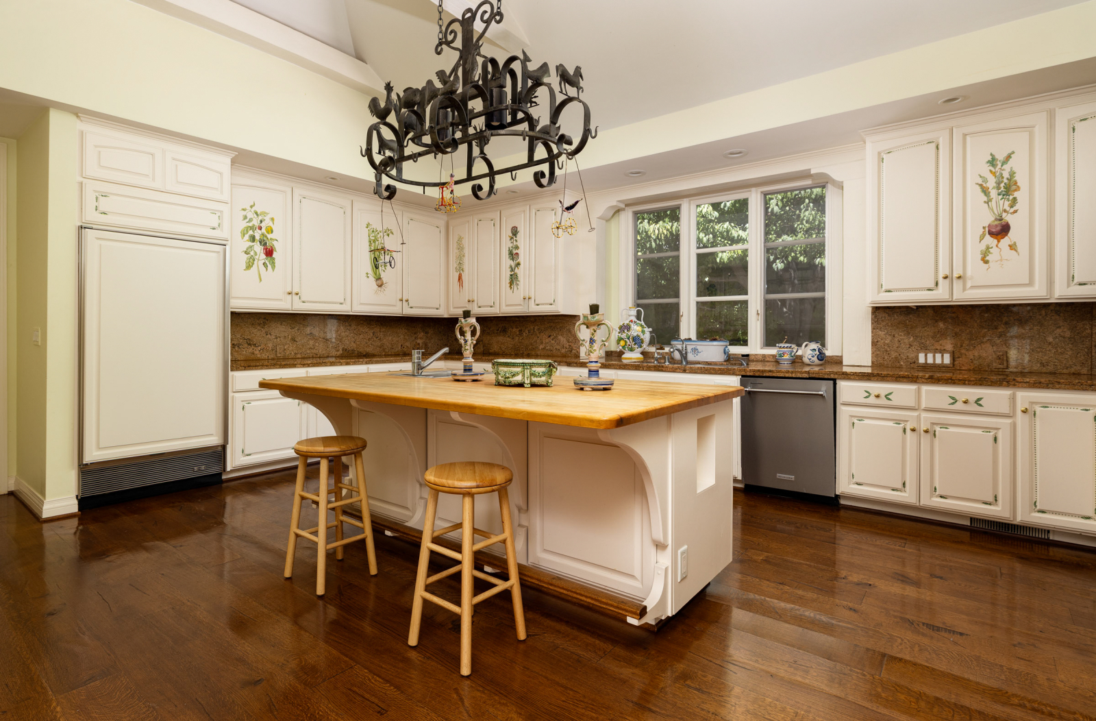 A gourmet kitchen with a magnificent iron chandelier, hand-stenciled cabinetry and an island in the center.