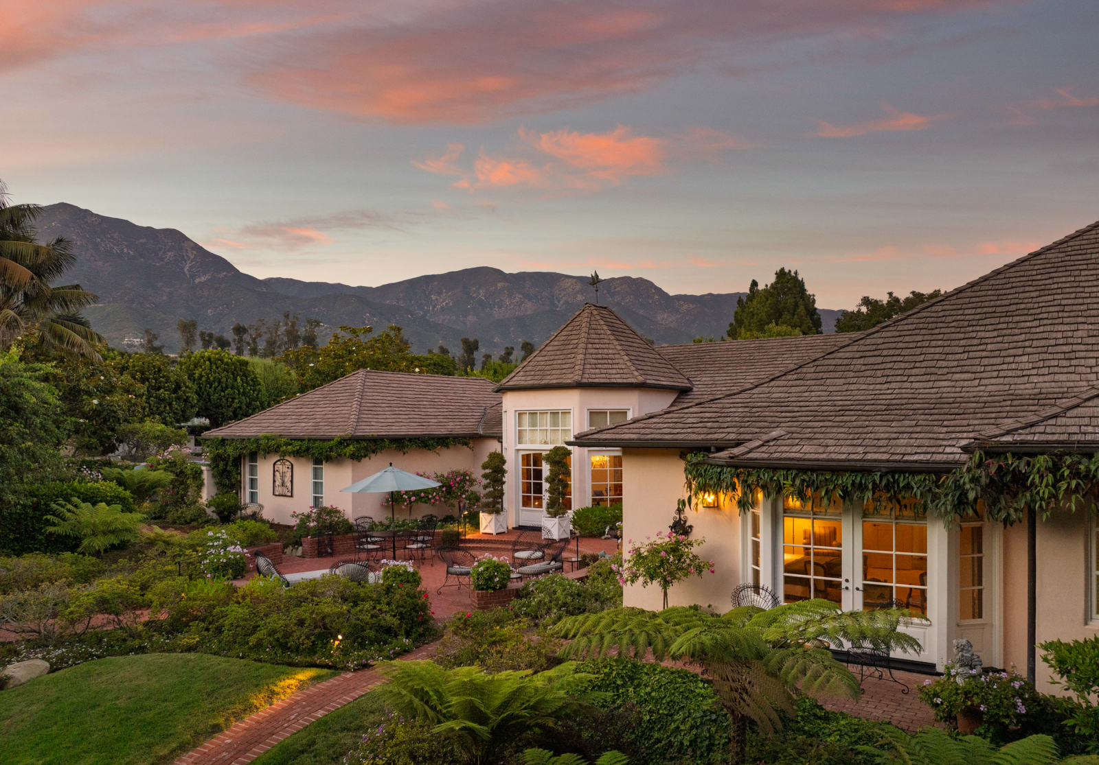The backyard of a luxury home set amist rolling golf fairways and majestic vistas under a beautiufl sky at sunset.