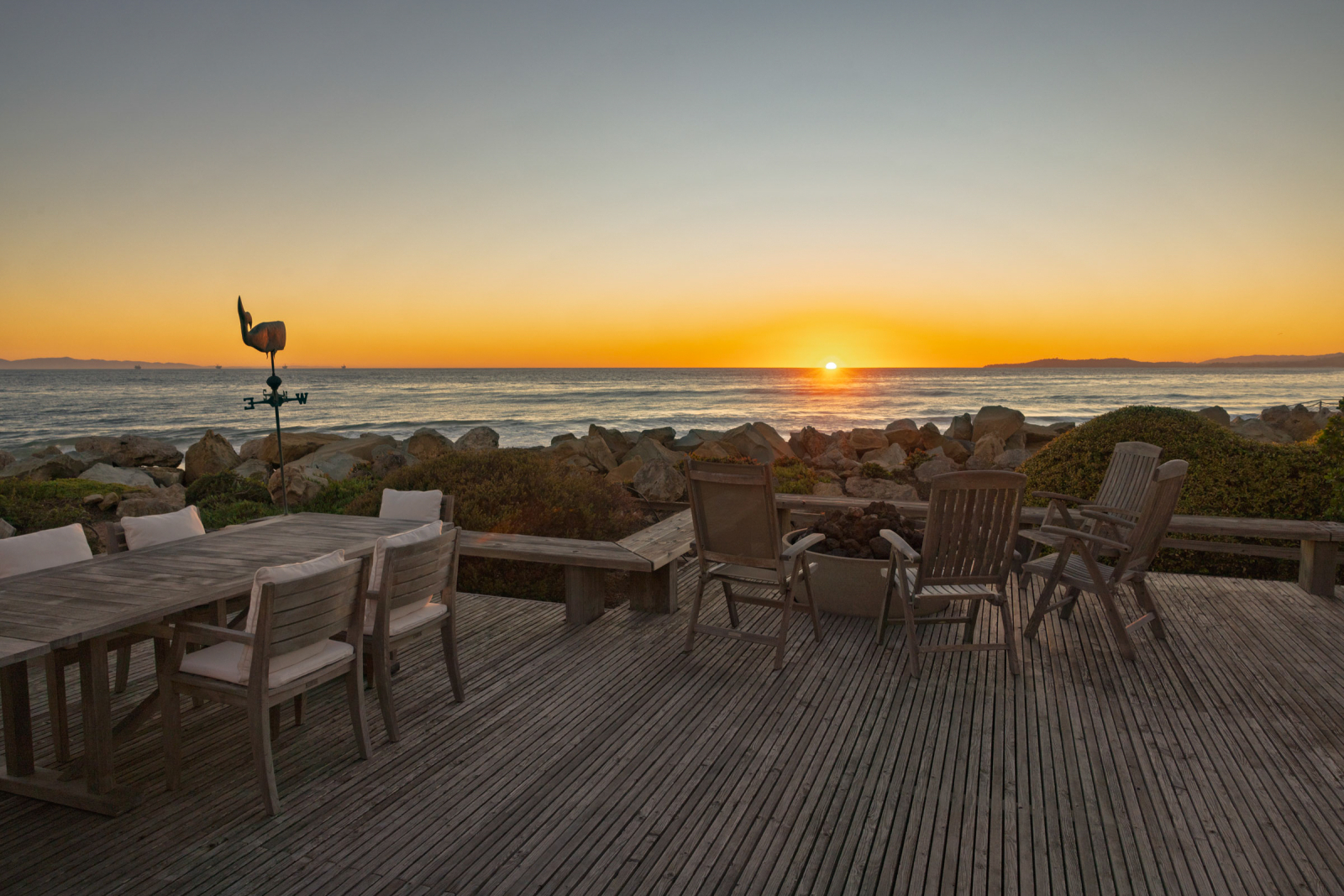 A wood dining deck on the sand at sunset.
