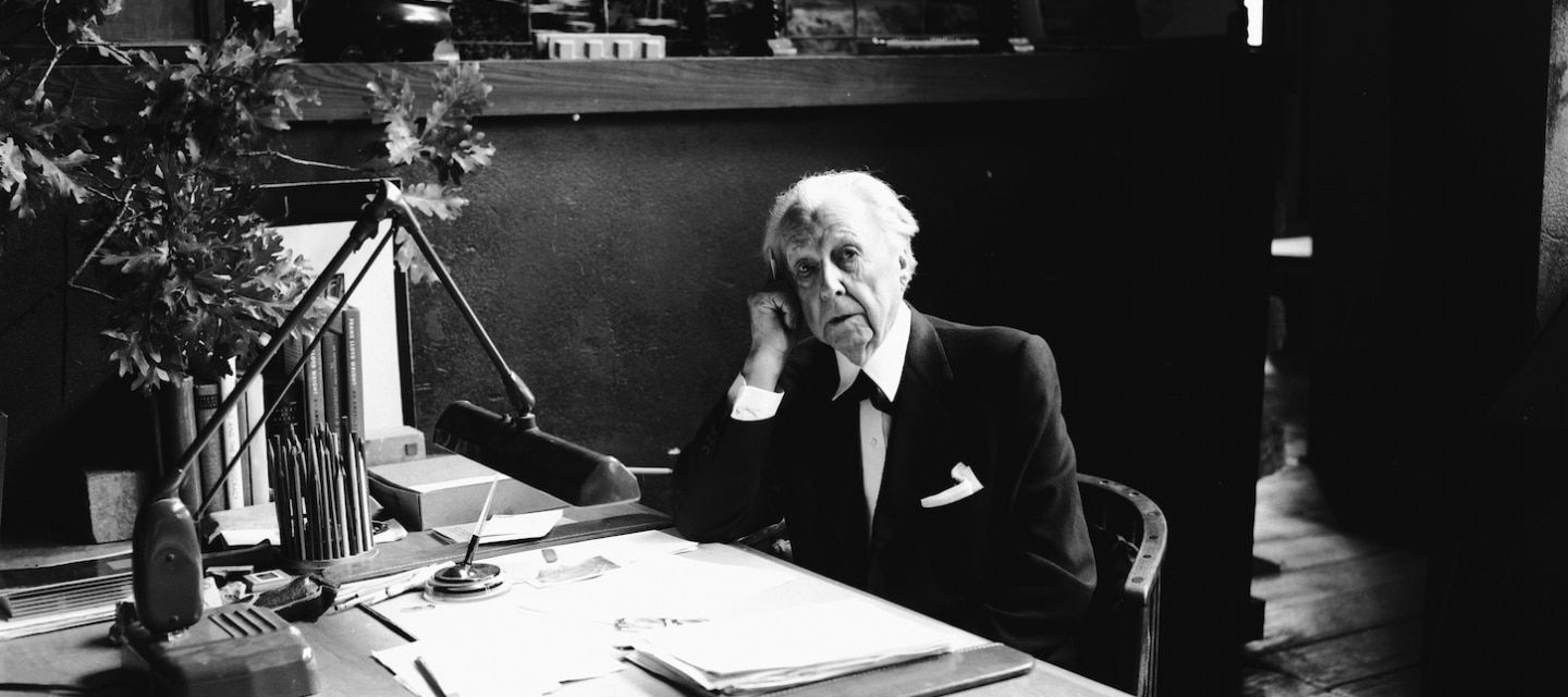 Architect Frank Lloyd Wright sitting behind a desk in his later years