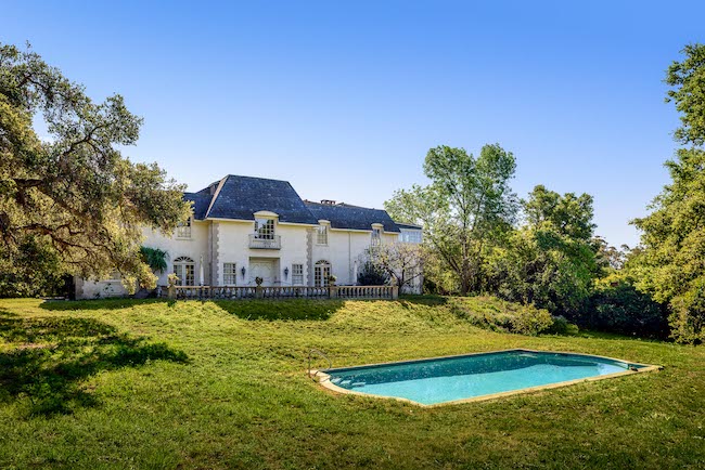 The back of an estate for sale with the sparkling pool in the foreground