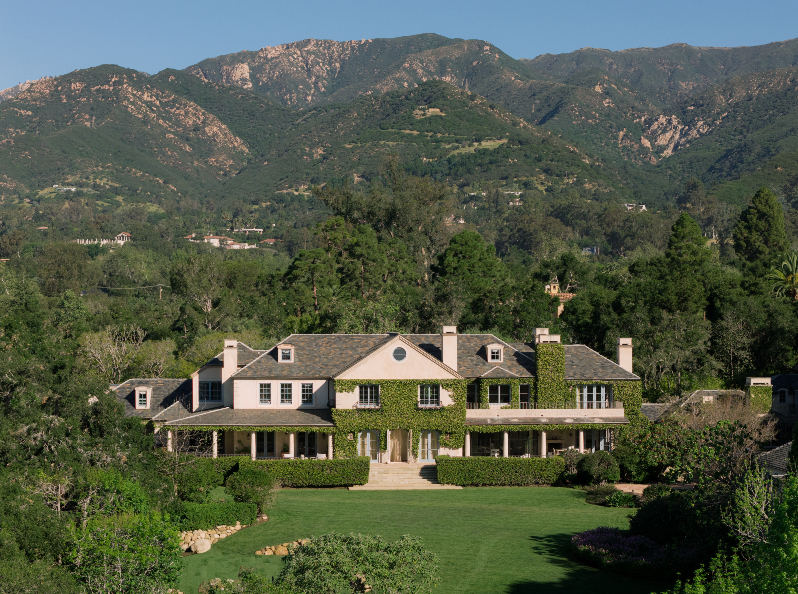 Elegant Montecito estate surrounded by lush landscaping and rolling lawns, with the Santa Ynez Mountains rising in the background.