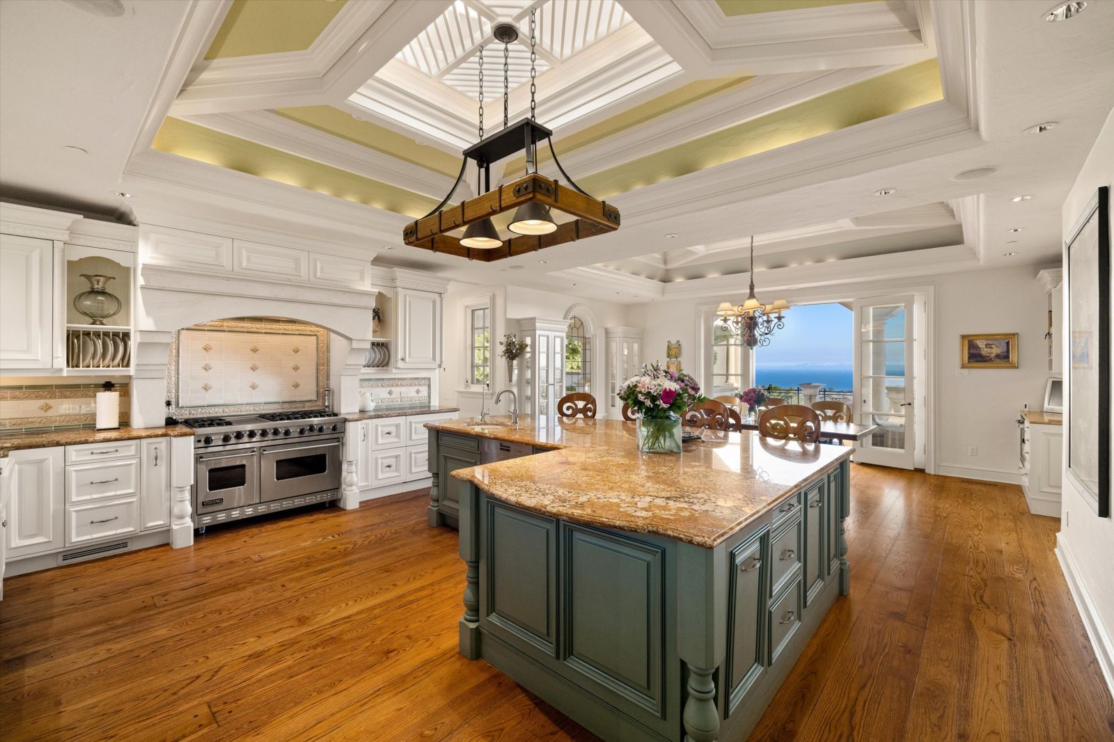 The luxury kitchen of a Santa Barbara home with a large center island, high-end stainless appliances, a large skylight, and a large window with ocean views.ocean views
