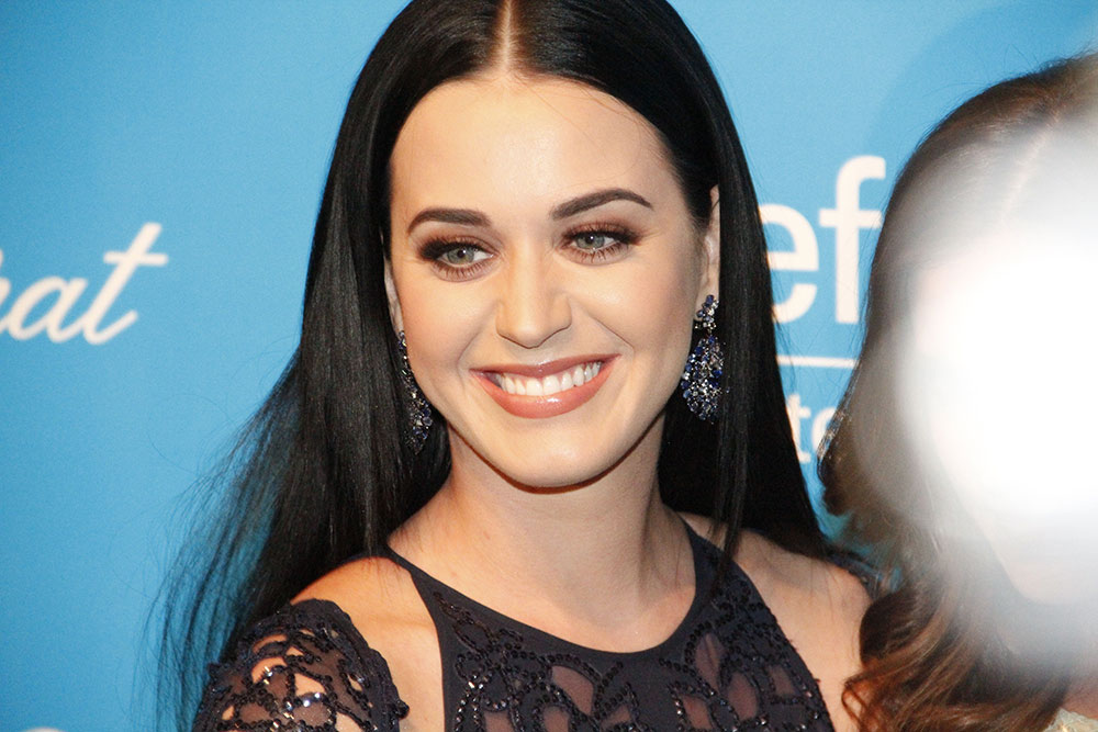 Popstar Katy Perry smiles on a step and repeat as photographer take pictures of her