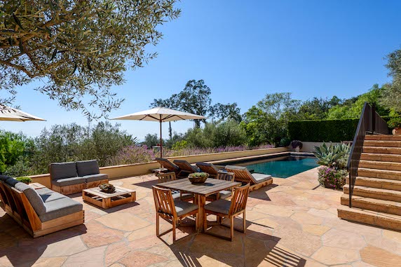 Backyard deck with luxury furniture, an umbrella, a firepit and a pool