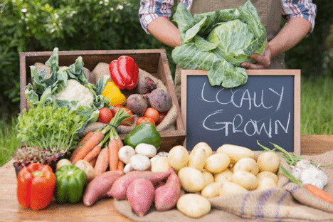 Fruits and vegetables at a local farmer's market with the sign locally grown