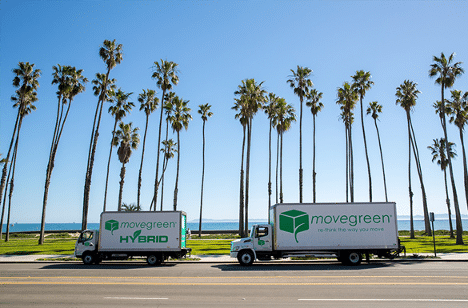 Green moving trucks in Santa Barbara in front of palm trees against a blue sky