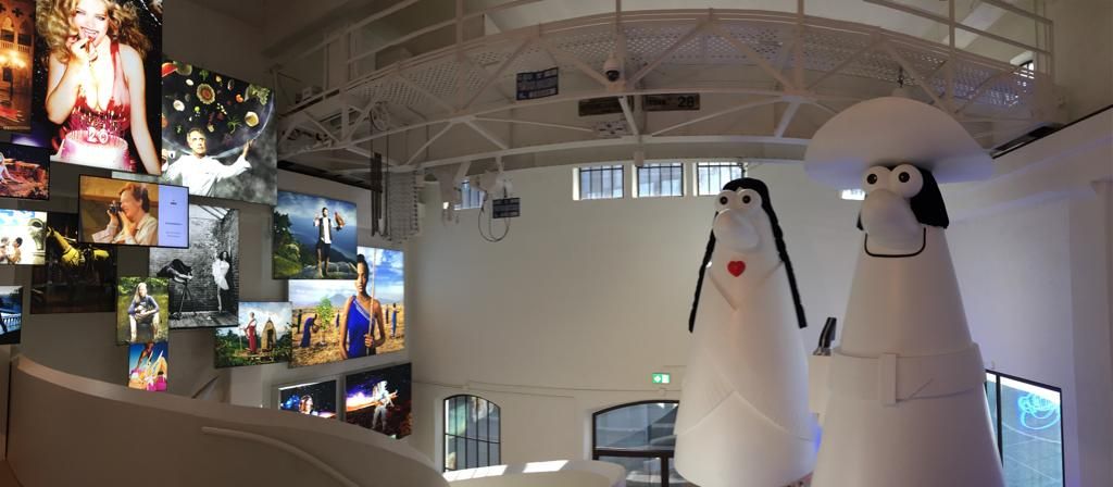 Inside an exhibit at the MOXI Museum with a wall of televisions and two statues.