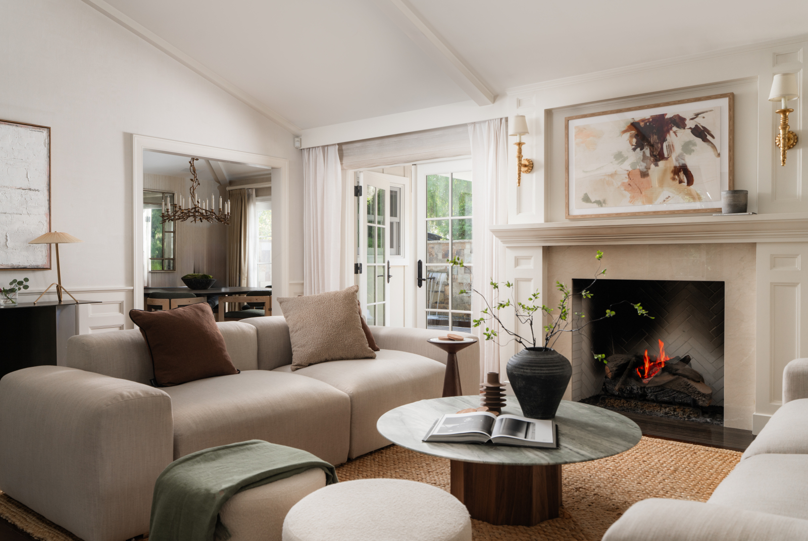 Elegant Montecito living room with neutral furnishings, a lit fireplace, French doors, and sophisticated contemporary décor.