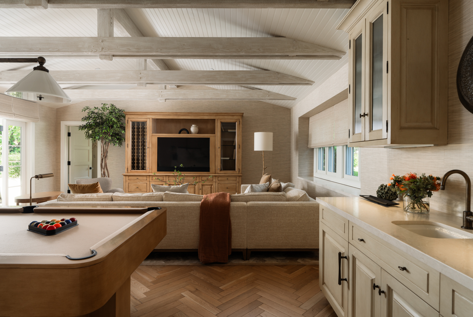Montecito family room with a pool table, built-in wet bar, comfortable seating, exposed beams, and warm wood floors.